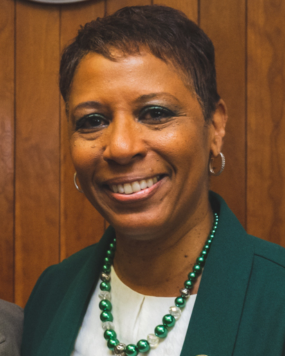 Photo of Adrienne Adams, smiling gently, in a green jacket, white shirt, and green necklace