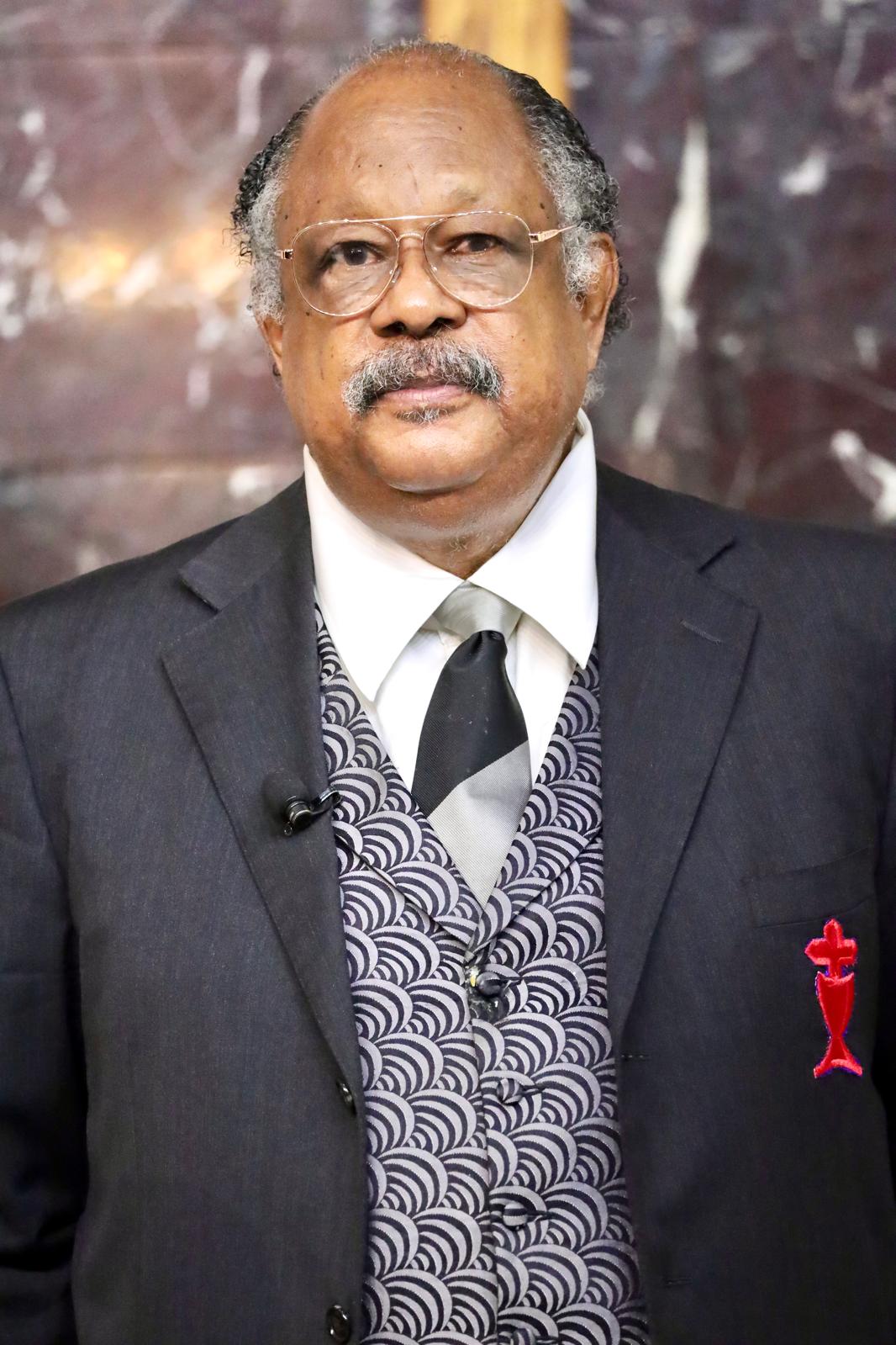 James Manning in a three piece suit looking at the camera with a thoughtful expression.
