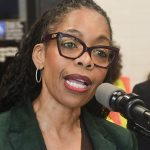 Photo of Rita Joseph speaking into a microphone, clearly engaged in making NYC more accessible