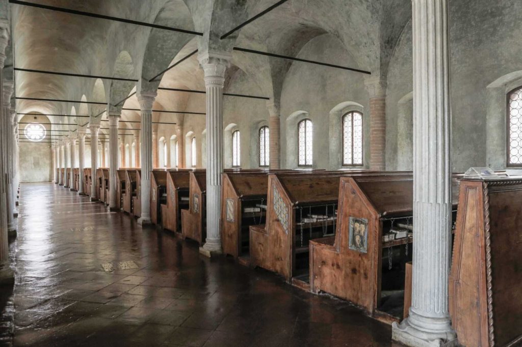Image of the interior of the Malatesta Novello Library. There are pew-like carrels in a vaulted room with pillars and tile floors