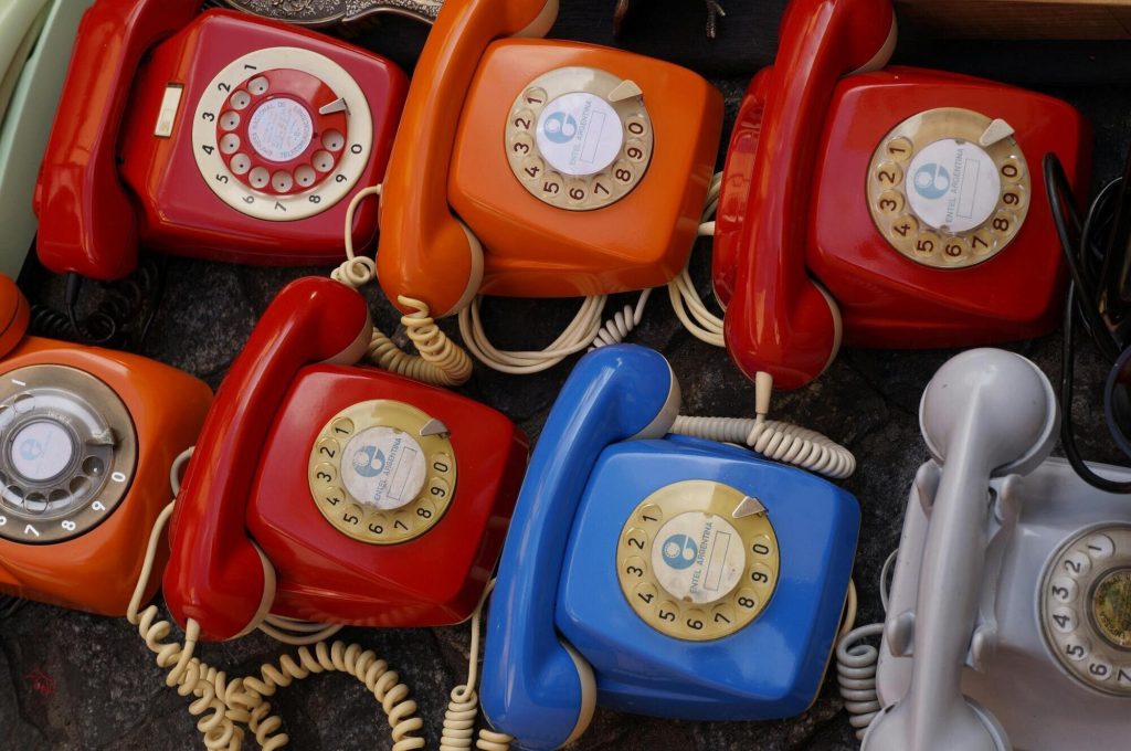 Overhead image of seven rotary telephones of various colors
